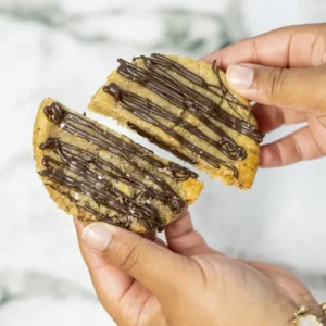 Photo d'un cookie au chocolat noir coupé en deux pour y voir son cœur fondant au chocolat